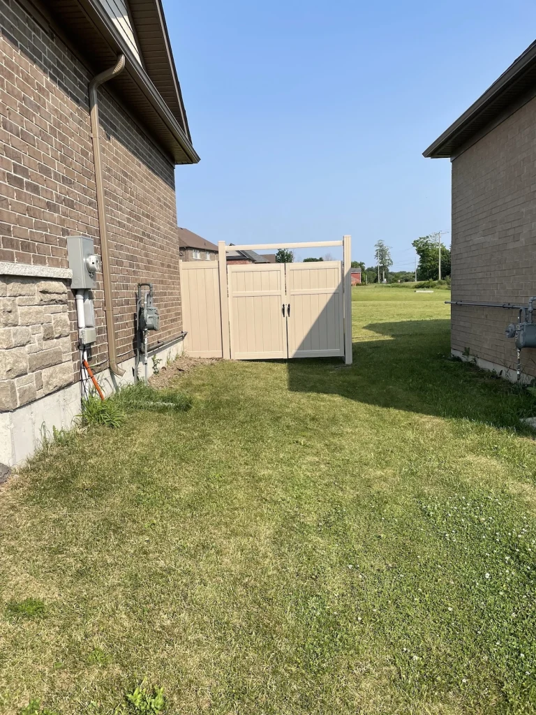 Wide-angle shot of a beige vinyl privacy gate installation for a residential side-yard in Whitby.