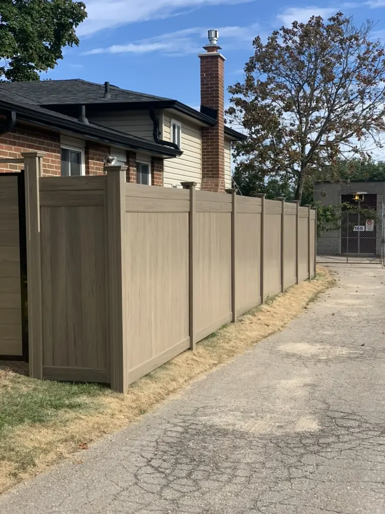 Professional installation of a beige vinyl privacy fence along a residential side yard for improved security.