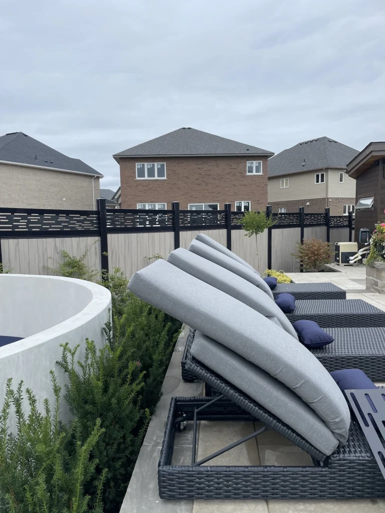 Beige vinyl privacy fence integrated with professional backyard landscaping in Stoney Creek.