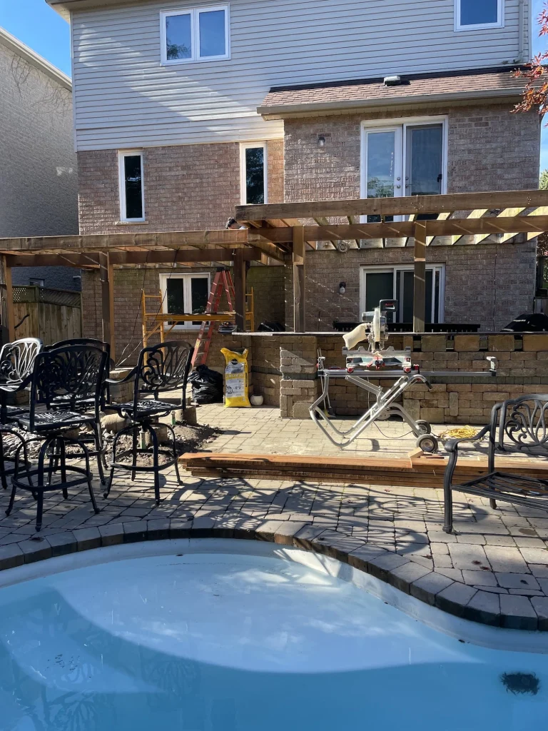 Professional wooden deck construction surrounding a backyard swimming pool in Bowmanville, Ontario.