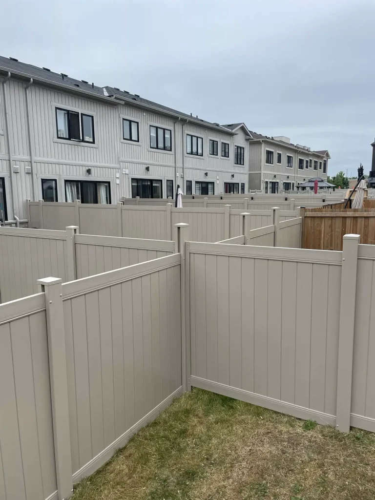 Large-scale beige vinyl fencing project across multiple properties in a new Bowmanville subdivision.