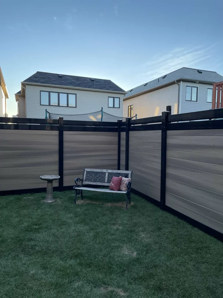 Textured brown vinyl fencing in Bowmanville shown during the evening to highlight the realistic wood-grain finish and durability.