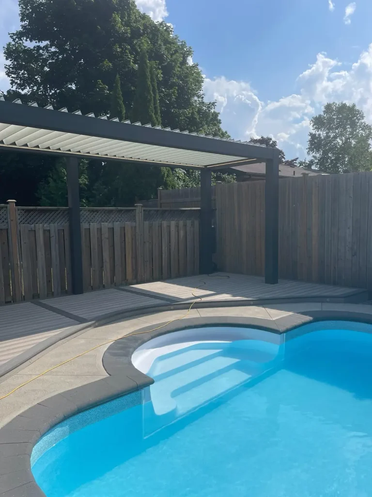 Custom composite deck and modern pergola installation poolside for a luxury backyard project in Peterborough, Ontario.