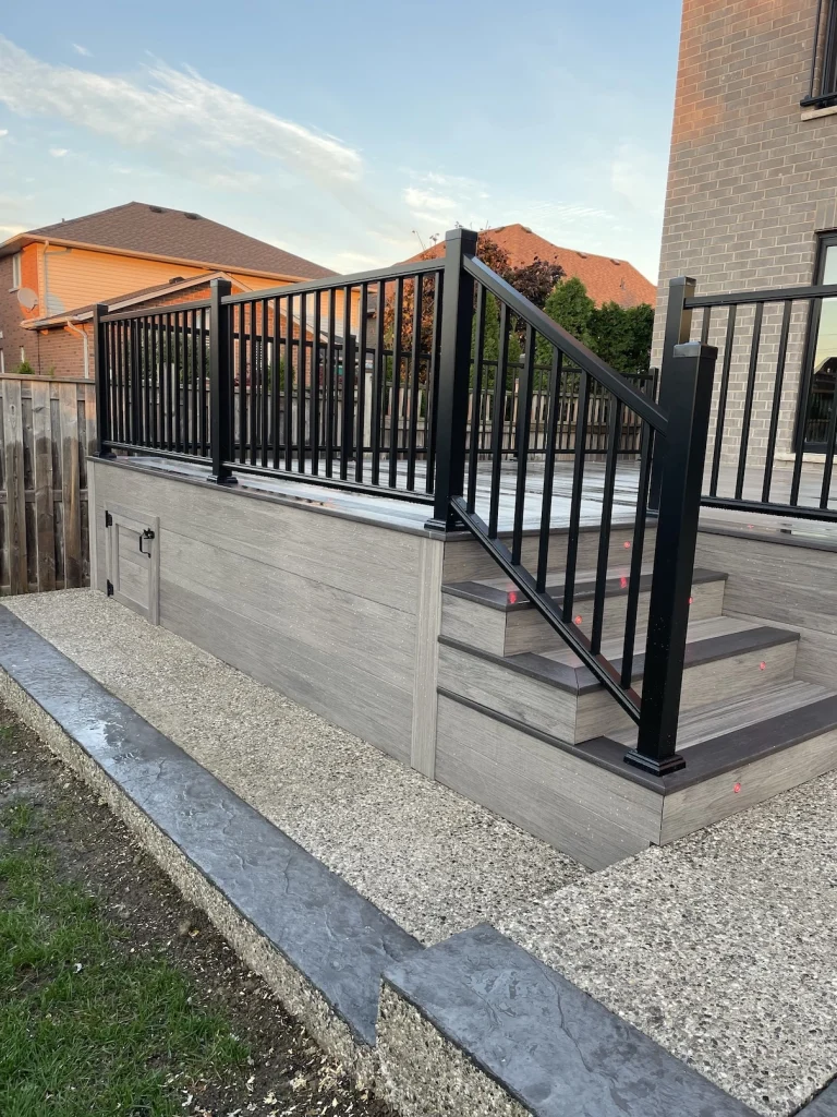 Sleek black deck railing integrated with professional backyard landscaping and stone features in Stoney Creek.