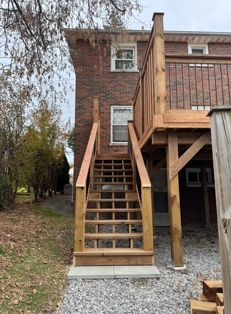 Raised pressure-treated deck in Oshawa featuring a high-contrast black aluminum railing system.