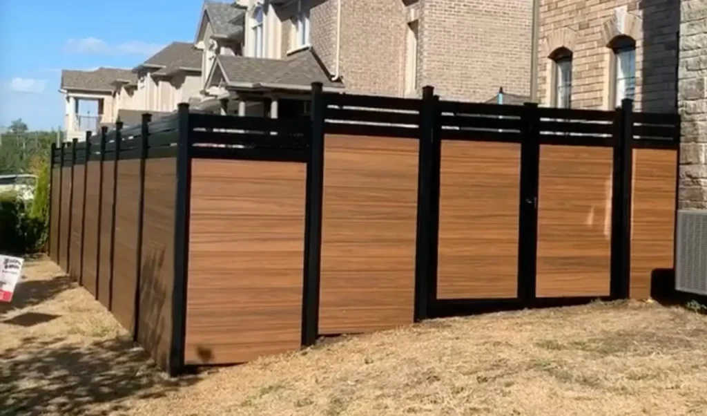 Contemporary woodgrain vinyl fencing with high-contrast black posts installed for a home in the Durham Region.