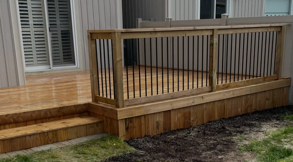 Pressure-treated wood deck railing with black metal spindles
