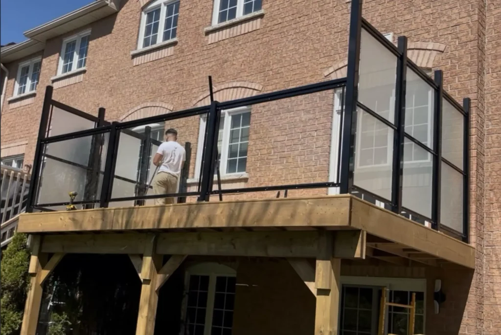 Elevated residential deck in Ajax featuring a black aluminum frame with clear glass inserts for unobstructed views.