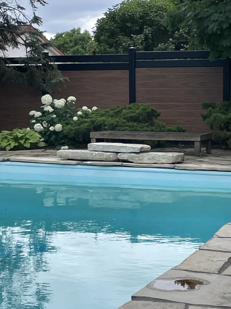 Two-tone brown vinyl fence with integrated stone pillars for an Ontario property.