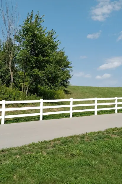 White vinyl ranch fence on a rolling green hill for an Ontario farm property.