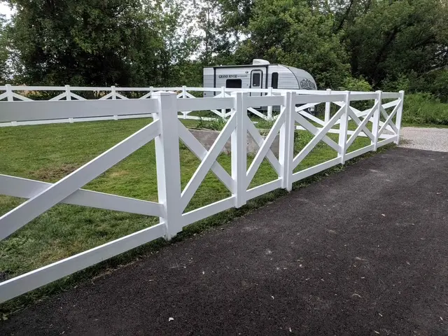 Traditional white ranch-style horse fence bordering a rural dirt road, showcasing high-visibility and weather-resistant vinyl construction